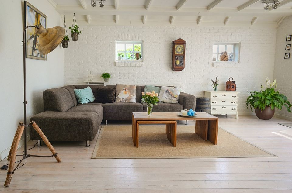 Bright living room with white walls, a gray sofa and wood beams