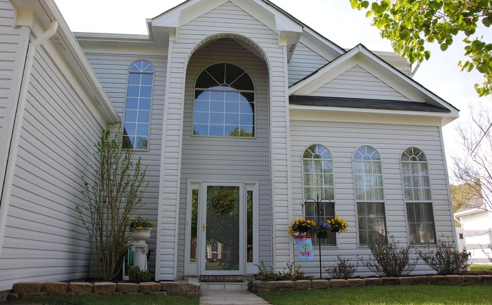Two-story house with white siding and an arched window
