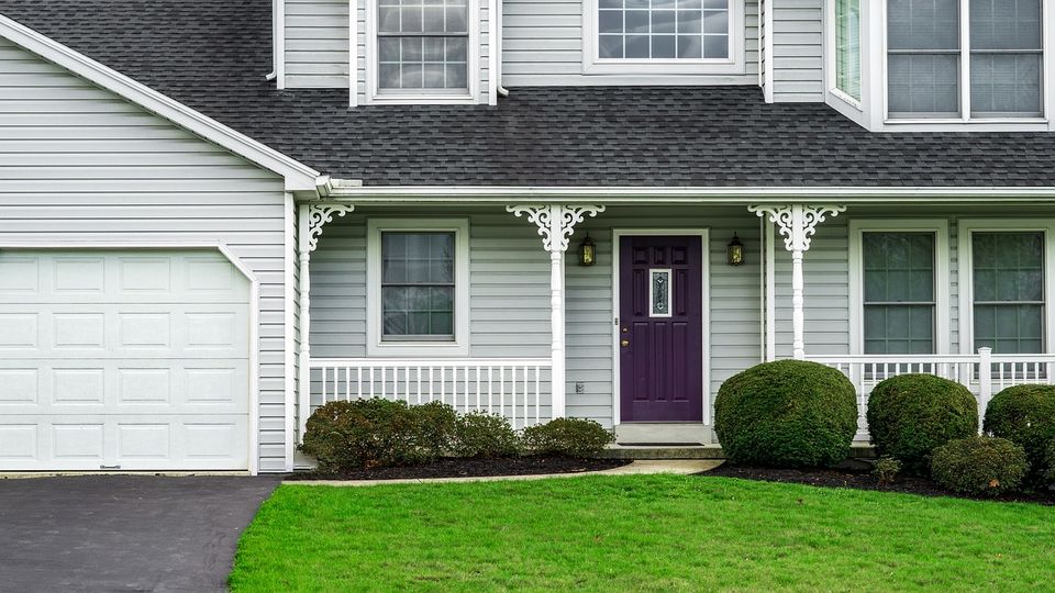 Suburban house with gray siding, white trim and a purple front door